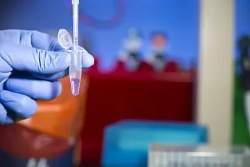 Gloved hand in a lab pipetting 