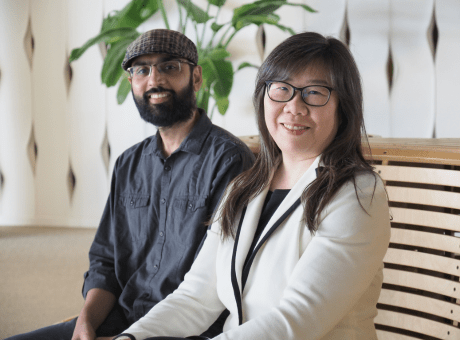 Salman Shahid (left) and Yu-Chien Wu (right) sitting on a bench smiling at the camera. A small tree is in the background.