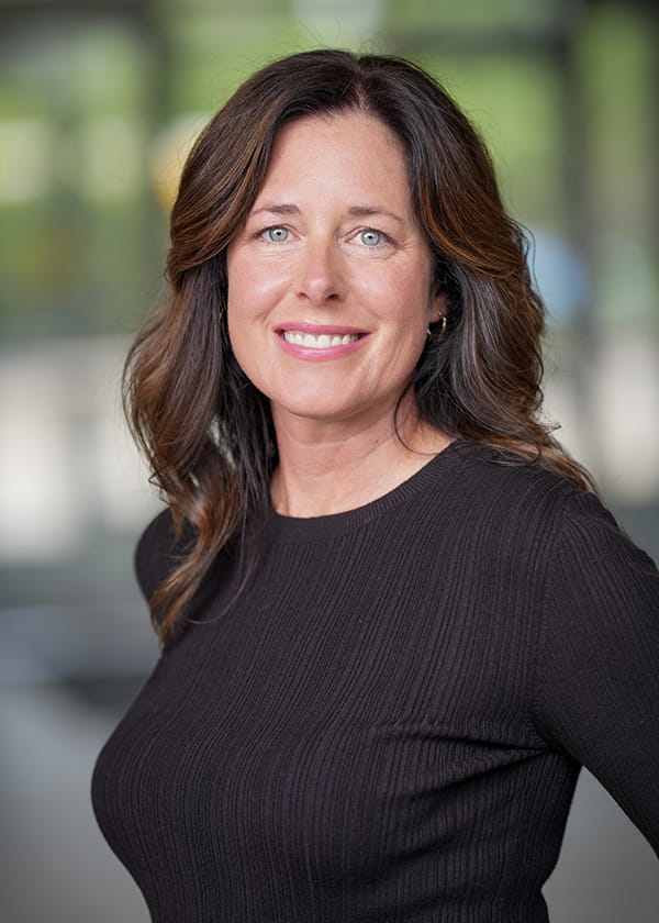 Picture of a woman wearing a black long sleeved shirt against a blurred background