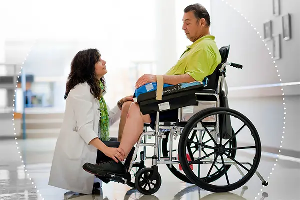 A photo shows a female physician kneeling in front of a patient in a wheelchair, showing compassion.