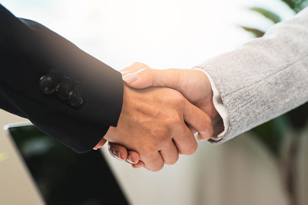 An image shows a close-up of two businesspeople shaking hands.