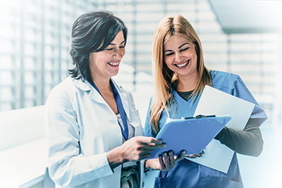 Two health care providers talk in a hospital setting