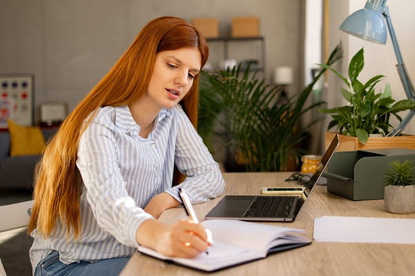 A woman takes notes while conducting research