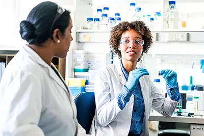 Two women discuss research in a lab