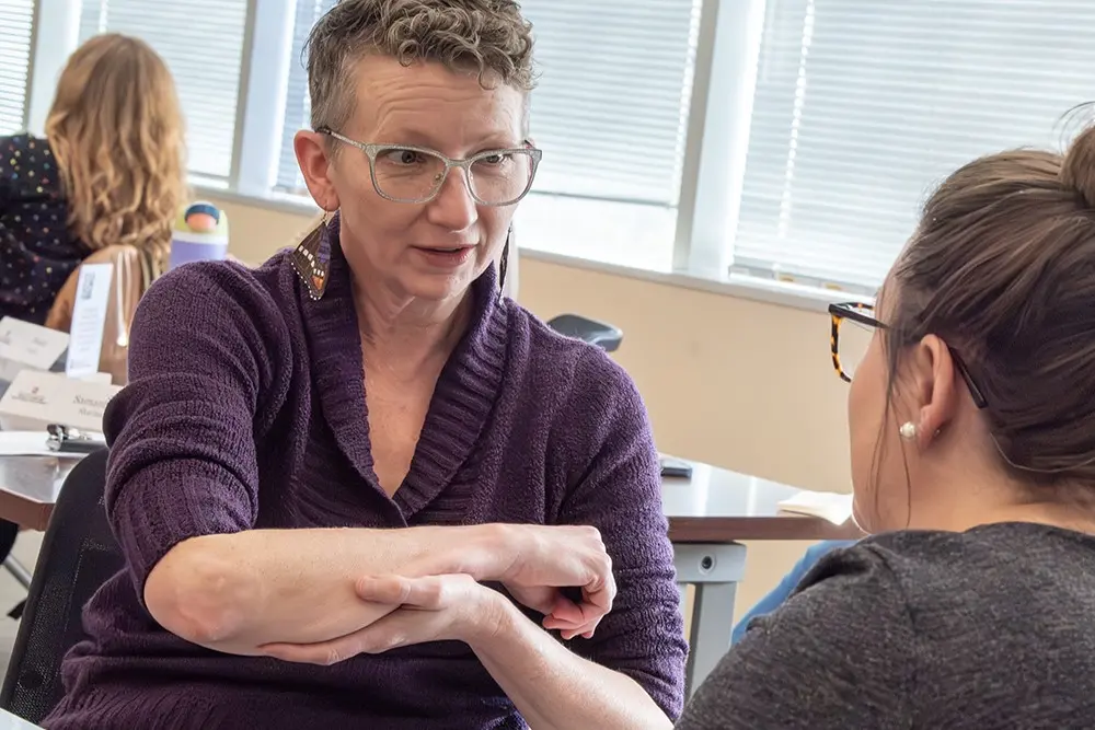 During an improv exercise called "Time Traveler," Kate Kollman, NP, a 2025 Communicating Science participant, attempts to explain — to a scene partner who plays the part of a person who lived more than a century ago — how X-ray technology allows someone to "see" a broken bone.