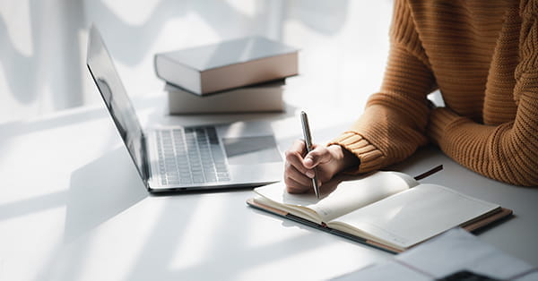 Scholar studying at a table with laptop and notebook