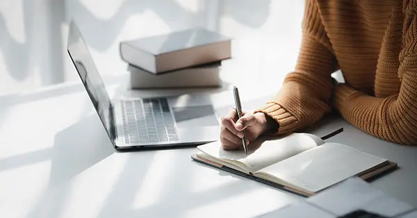 Scholar studying at a table with laptop and notebook