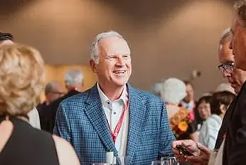 an older man with white hair smiles in the midst of a celebration