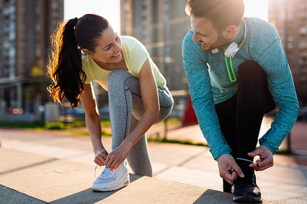 Man and woman lace up running shoes