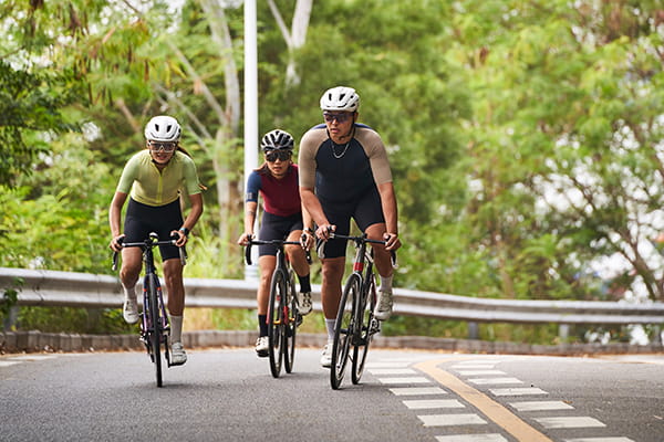 A group of adults ride bicycles on a road
