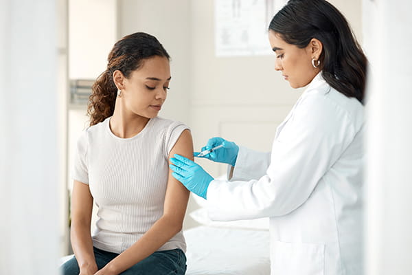 A young female patient receives an immunization from a female physician