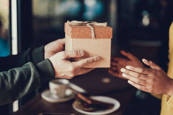 Two people exchange a paper-wrapped gift. 