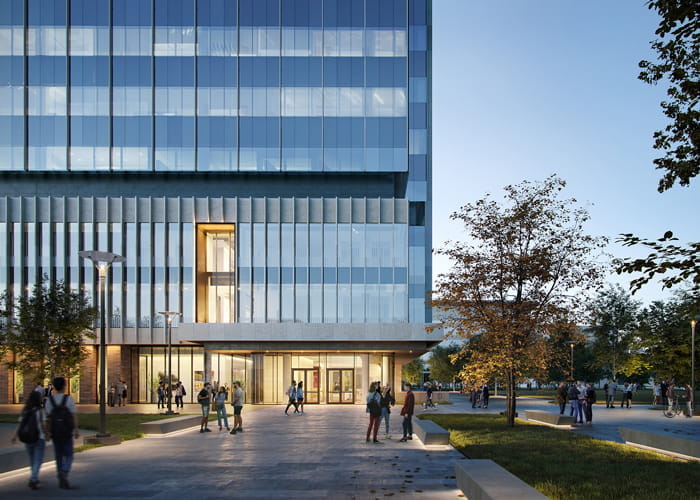 the back of the new building with people gathering outside at twilight