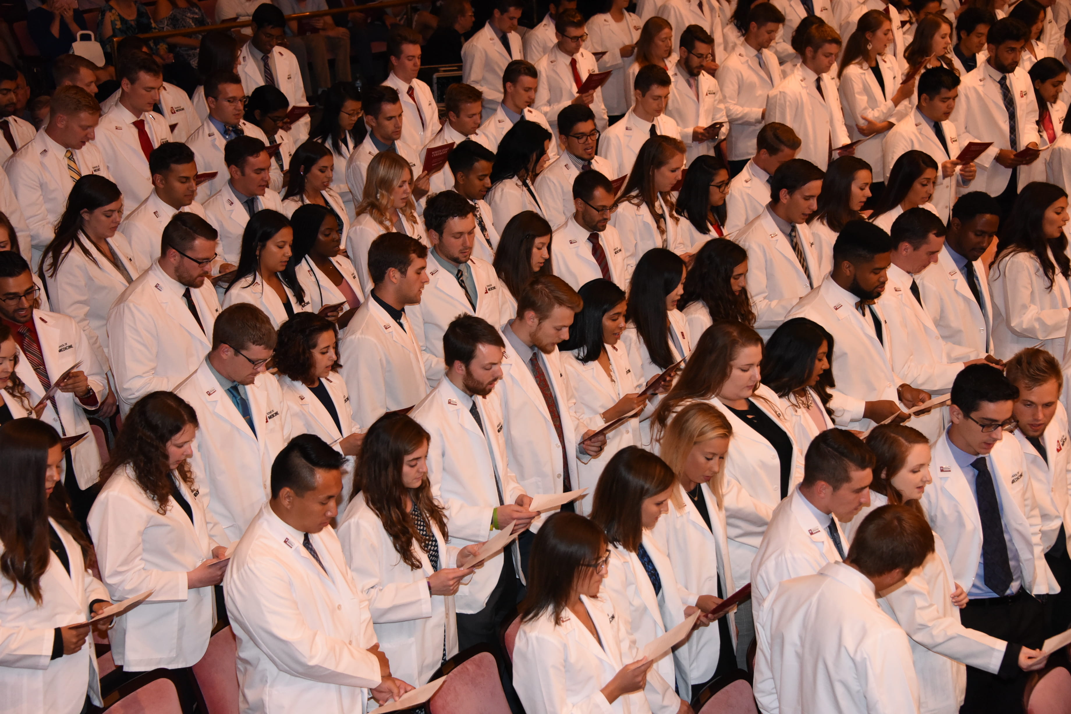 Medical students recite an oath at a white coat ceremony.