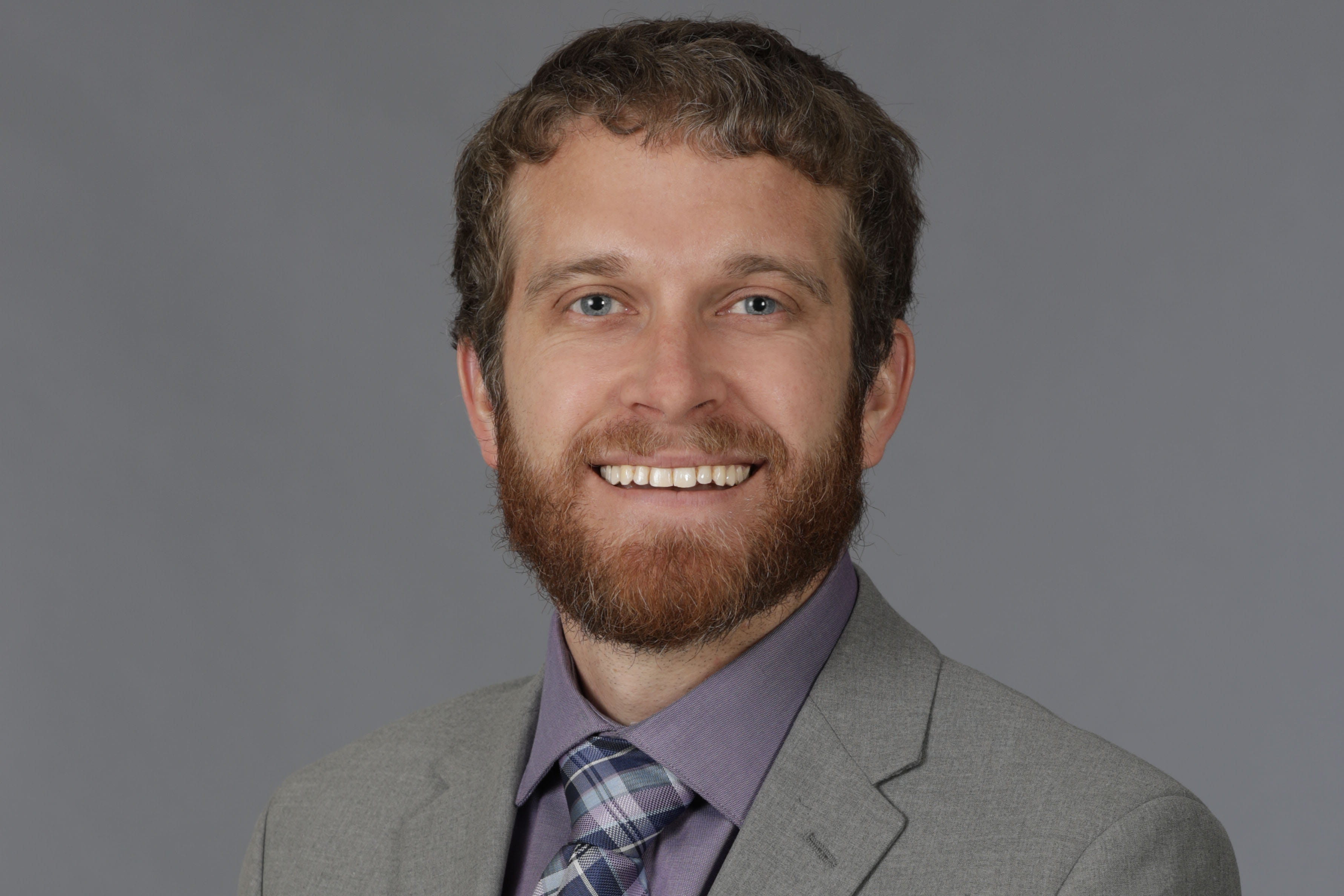 A man in a suit smiles. 