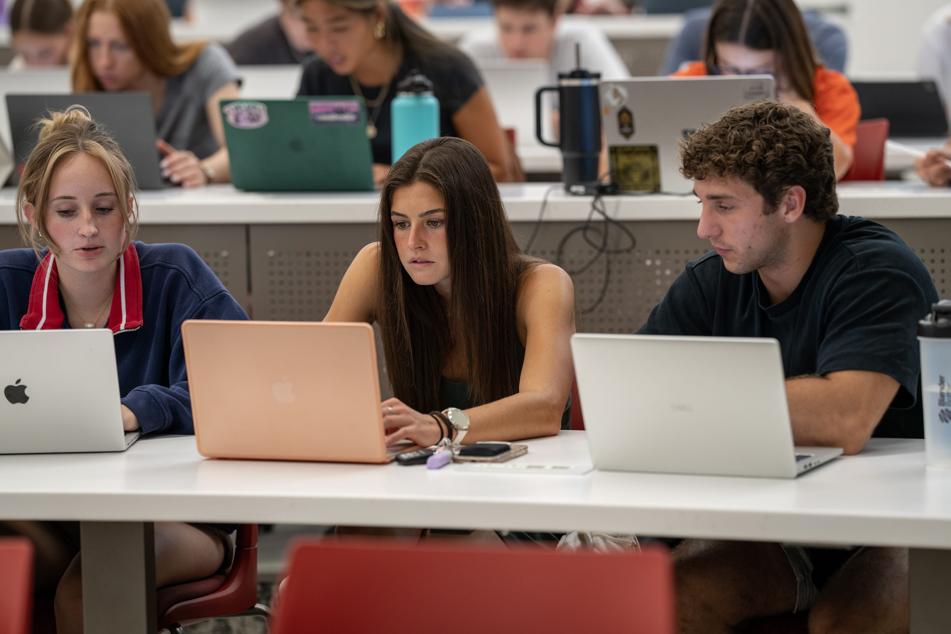 Three students sit with laptops. 