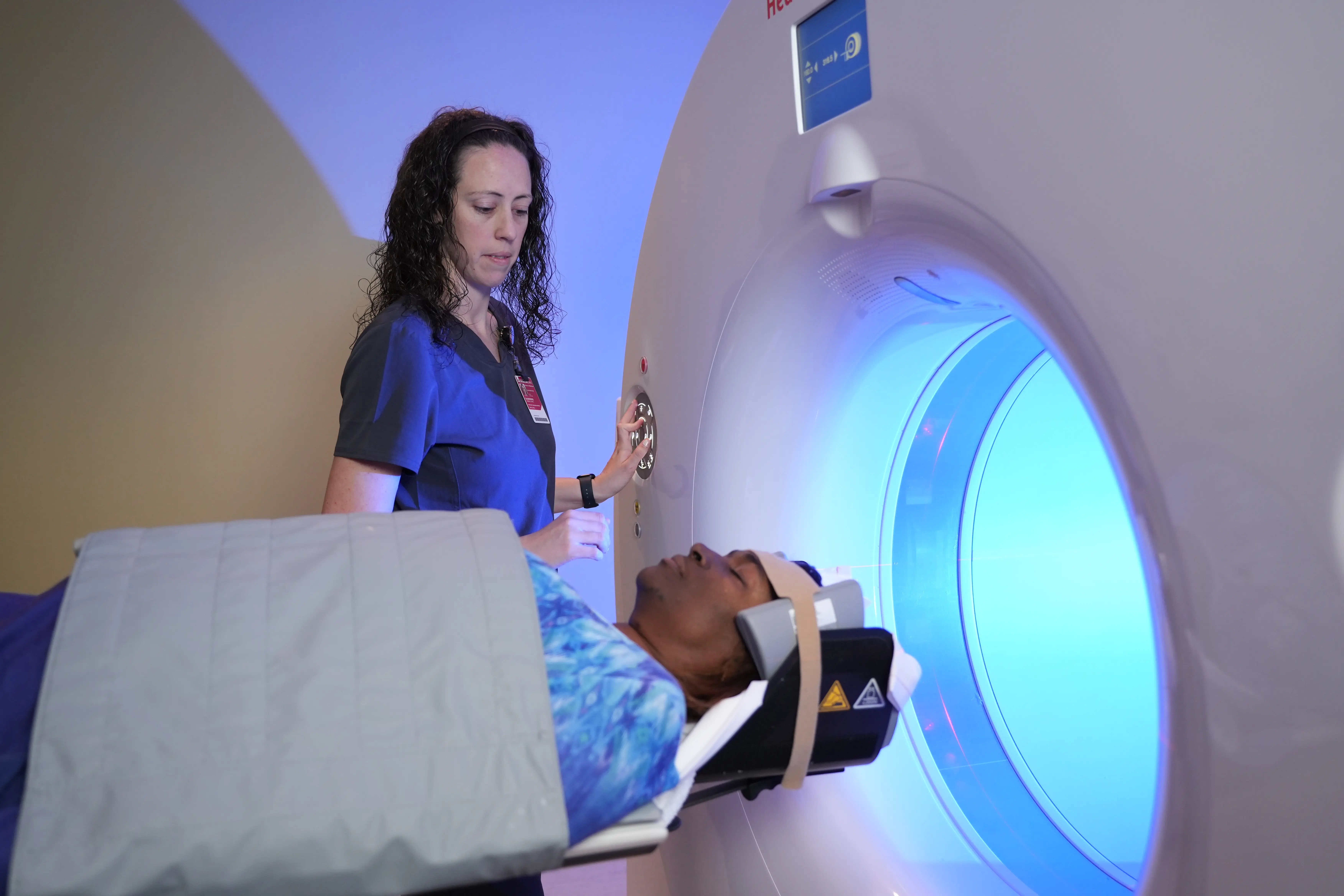 A female technologists performs an MRI scan on a female patient.