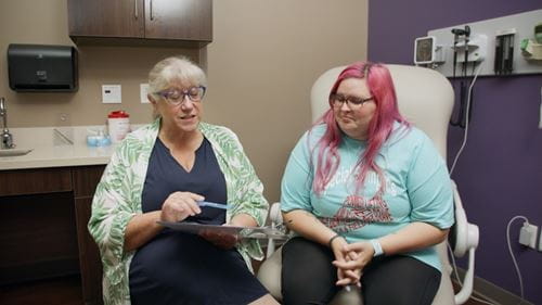 female doctor with clip board going over information with female patient