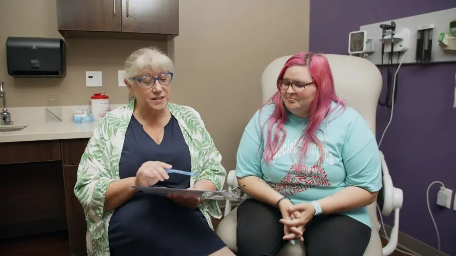 Doctor using clip board to explain care to patient sitting in chair