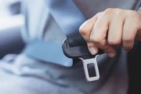 person buckling themself in a car