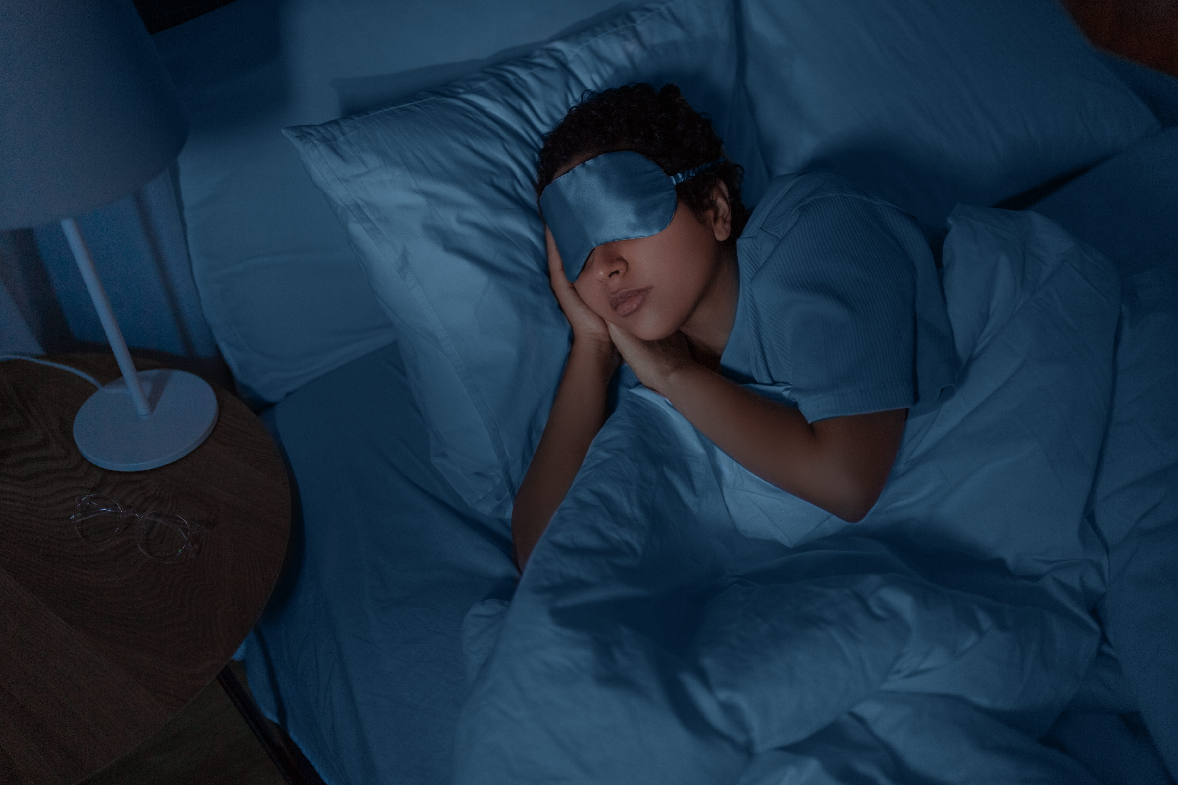 woman sleeping in dark room with eye mask on