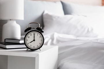 alarm clock next to a bed