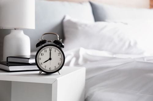 alarm clock next to a bed