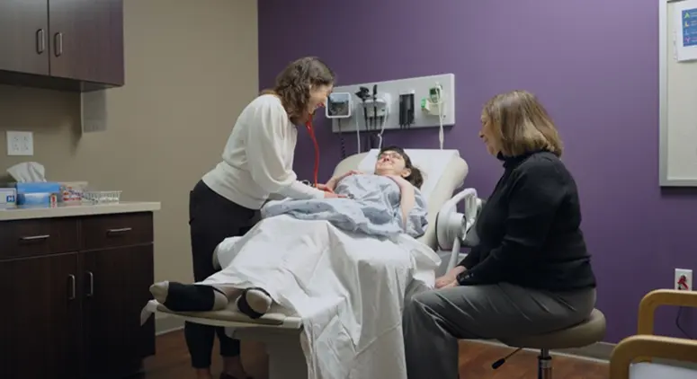 female doctor examining the belly of a female patient and female caretaker