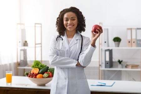 african american female dietician holding a piece of fruit in a kitchen