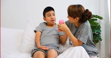 boy using weight in hand with assistance of caregiver