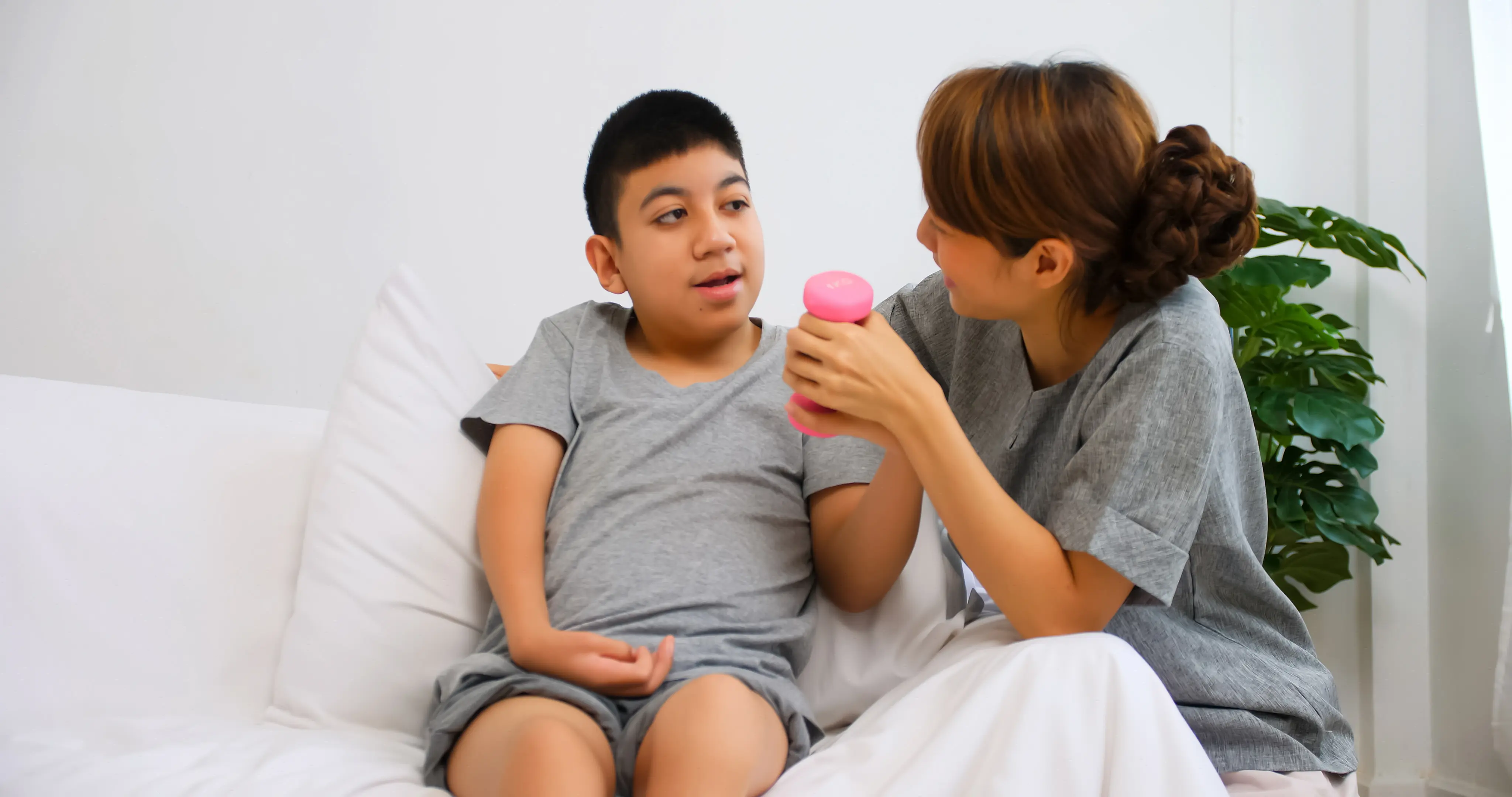 boy using weight in hand with assistance of caregiver
