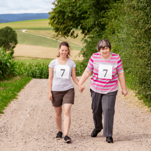 Woman with intellectual disabilities walking with female caregiver