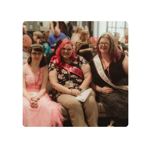3 female friends with intellectual disabilities sitting on a couch smiling for the camera