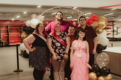 group of women and men with disabilities standing in front of a photo backdrop for a red carpet event