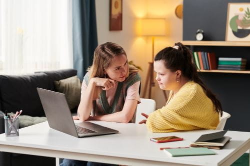 two women, one with an intellectual disability, having a discussion looking at a computer