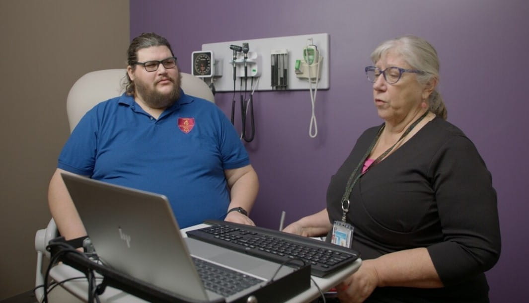 man with intellectual disability meeting with his female primary care doctor reviewing a treatment plan on a laptop