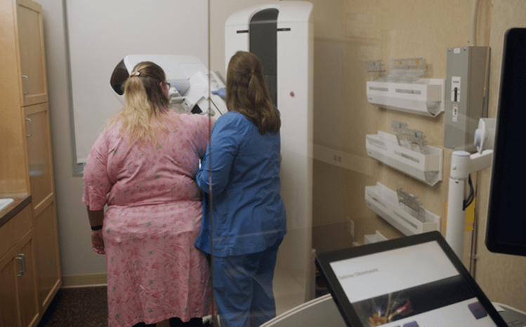 Woman patient getting ready for a mammogram exam with a female  clinician