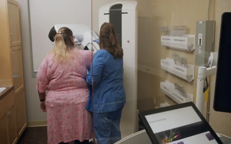 Woman patient getting ready for a mammogram exam with a female  clinician