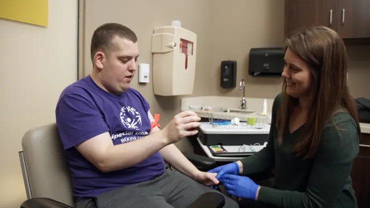man with intellectual disability works with female nurse on getting a needle stick