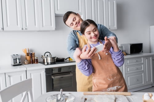 male and female with intellectual disabilities enjoying time together cooking and looking at a phone