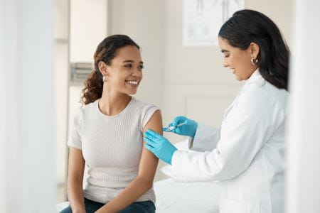 woman doctor giving a woman patient a vaccine