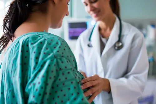 female doctor performing breast screening on female patient 