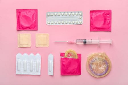 different contraceptives on pink colored background
