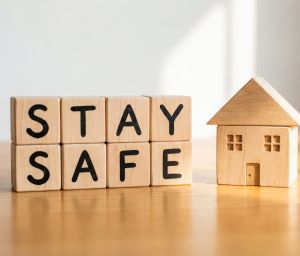 stay safe word letters next to a wooden house