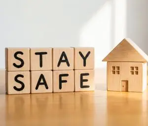 stay safe word letters next to a wooden house
