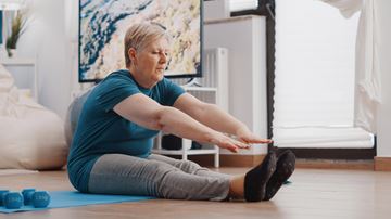 woman sitting on the floor reaching for her toes