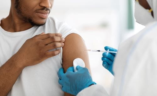 African American male getting a shot from a nurse