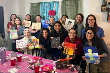 residents hold up their paintings after a group art outing