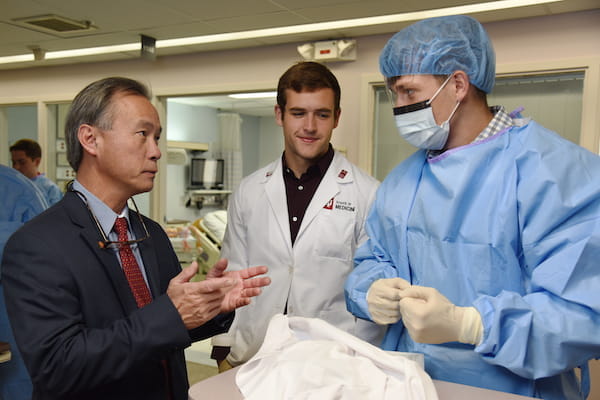 Dr. Duong with two students; one is in surgical scrubs
