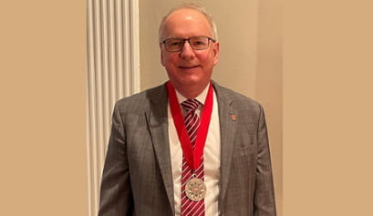 Dean Hess smiling for the camera with the IU President's Medal for Excellence around his neck